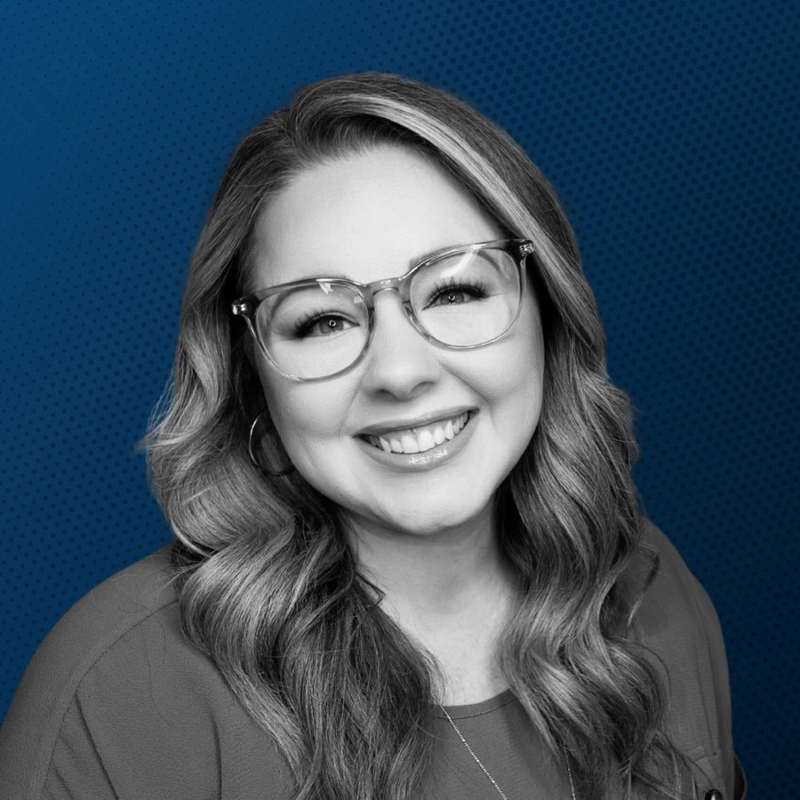 Katie Moreno smiling, wearing clear-framed glasses, on a navy background